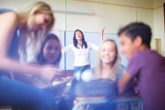 Frustrated teacher and talking students in classroom