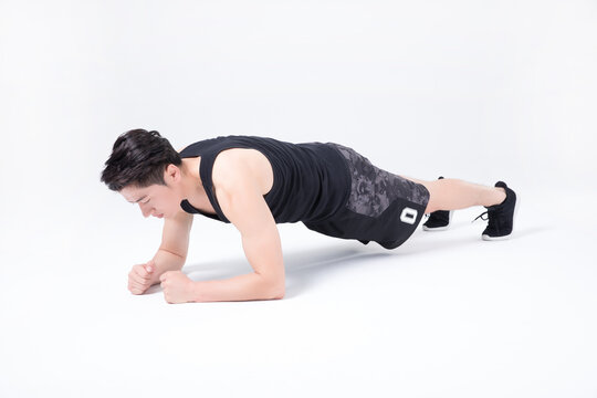 Young man doing forearm plank exercise in studio