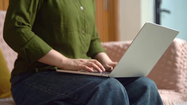 Indian woman typing on laptop keyboard closeup while working from home