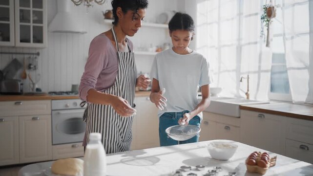 African american mom and daughter cooking together in weekend, baking cookies. Happy family spending time together, single mother and her teen child making dough for pie or cake for family fest
