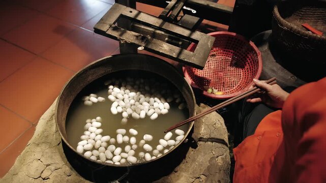 Boiling silkworm cocoons for silk thread production in a traditional craft workshop in vietnam