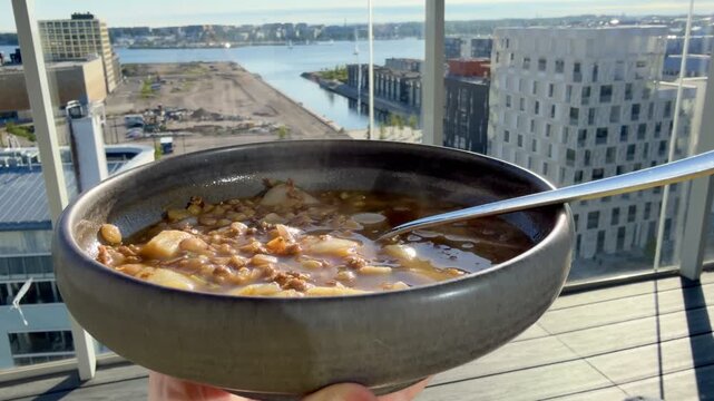 Horizontal 4K Close Up of Steaming Lentil Soup on Outdoor Balcony with J&auml;tk&auml;saari Rooftops Background