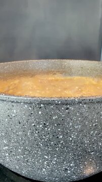 Slow food concept: Vertical Side View of Boiling and Steaming Lentil Soup in Pot 