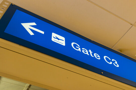 A blue sign hanging on the ceiling of an airport with an arrow to Gate C3