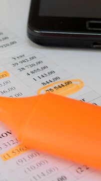 Finance professional reviewing company expenditures. Marked figures on a printed budget report. Business decision-making, financial sustainability, and profitability optimization