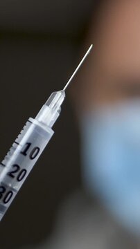 Medical professional in surgical mask extending syringe with liquid drug. Immunization as key health measure. Vaccination ensuring patient safety. Reliable medical procedures for disease prevention