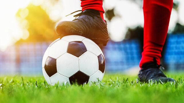 Action closeup of soccer cleat shoe stepping on classic ball in pitch before match kickoff with beautiful lens flare