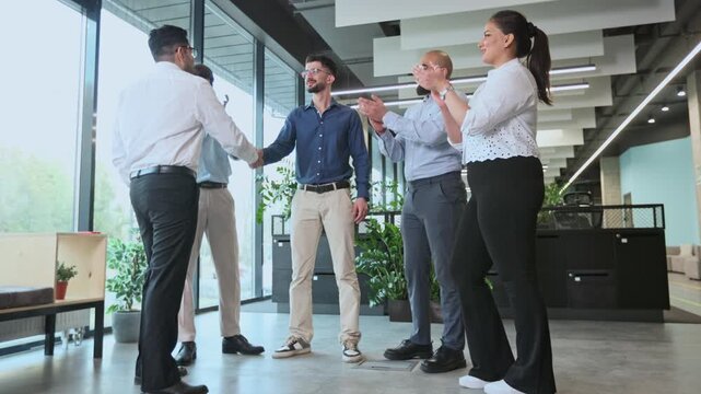 A group of men are standing in a room, one of them is wearing a blue shirt
