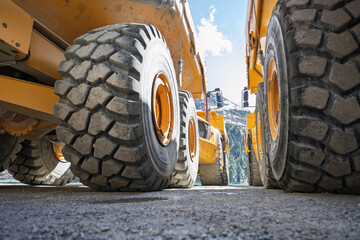 Low-Angle View of Massive Mining Dump Truck Wheels, Industrial Heavy Equipment in Alpine Landscape, Power and Engineering Concept © ikoon