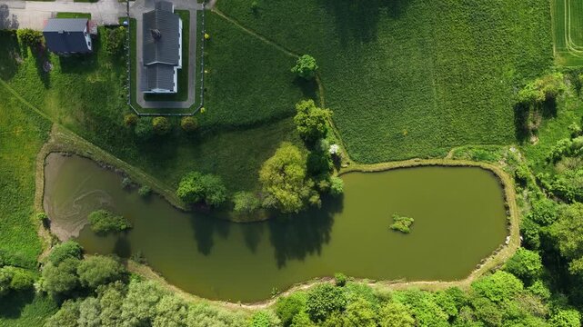 Aerial drone view of Chlina village in Silesian Voivodeship, Poland, featuring historic church, agricultural fields and rural countryside landscape during a sunny spring season. Church near the lake