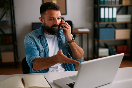 Frustrated businessman discussing problem during phone call while working remotely