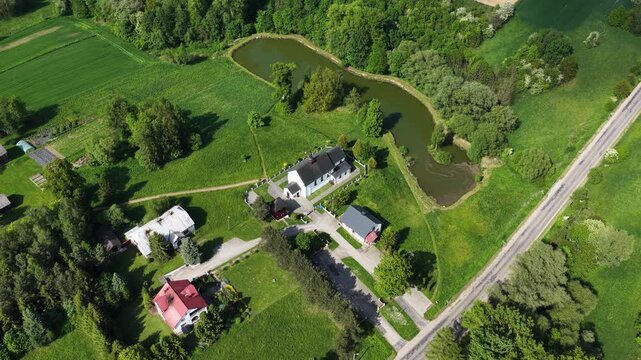 Aerial drone view of Chlina village in Silesian Voivodeship, Poland, featuring historic church, agricultural fields and rural countryside landscape during a sunny spring season. Church near the lake