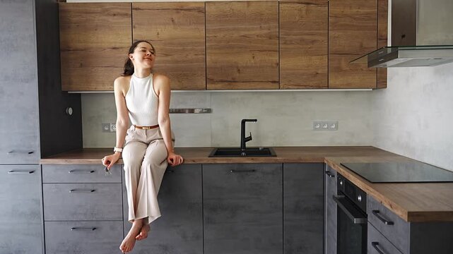 Young woman with apartment keys sitting in furnished resale apartment kitchen. Secondary housing purchase and moving into existing property concept