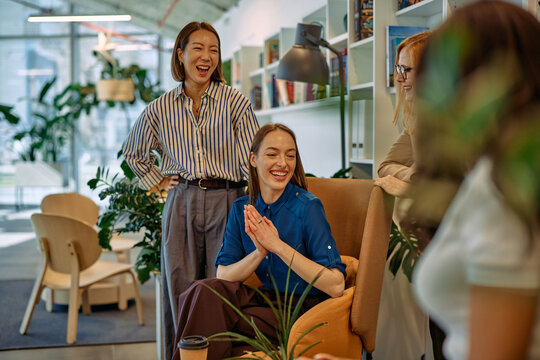 Coworkers laughing during informal office meeting