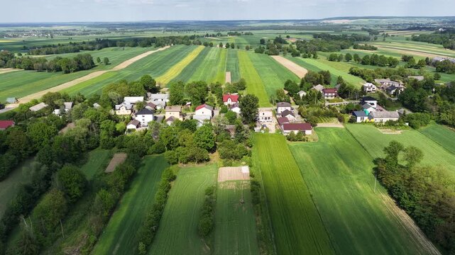 Aerial drone view of Chlina village in Silesian Voivodeship, Poland, featuring historic church, agricultural fields and rural countryside landscape during a sunny spring season. Church near the lake