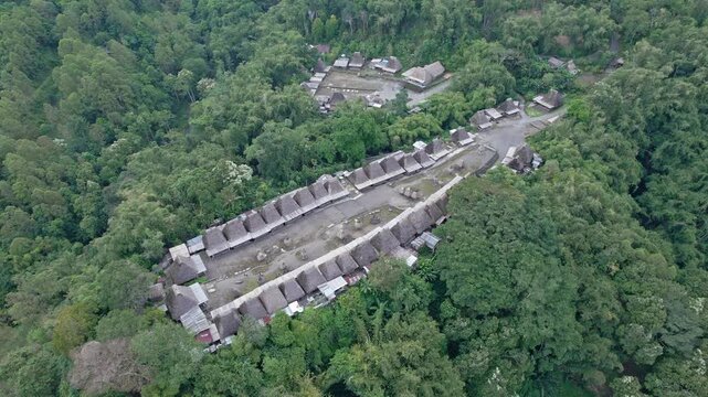 Aerial view of Bena Traditional Village with thatched roof houses surrounded by lush green forest in Kecamatan Jerebuu, Nusa Tenggara Timur, Indonesia.