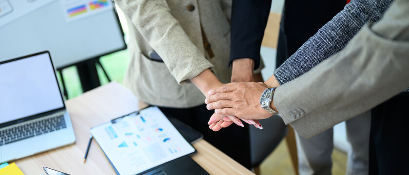 Business Team Stacking Hands Together in Office Meeting, Showing Unity and Teamwork