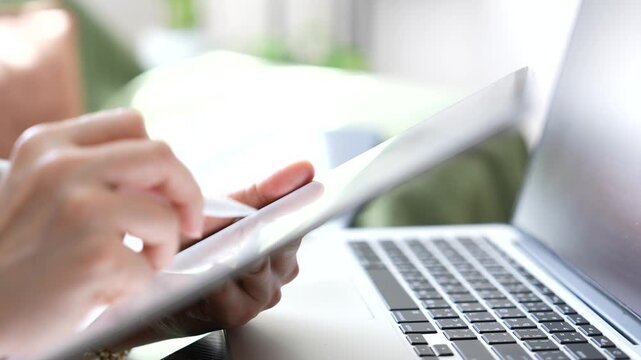 Close up hand checking email on tablet beside laptop in modern workspace. Digital communication, inbox management, online correspondence and mobile productivity for business workflow.