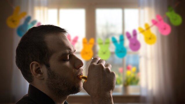 Man drinking alcohol at home with Easter bunny decorations in background