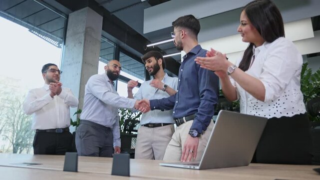 A group of men and women are standing around a table with a laptop on it