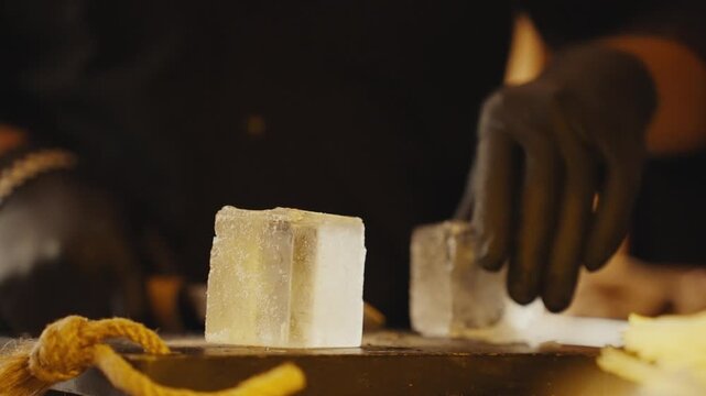 Professional bartender carving ice cube for cocktail