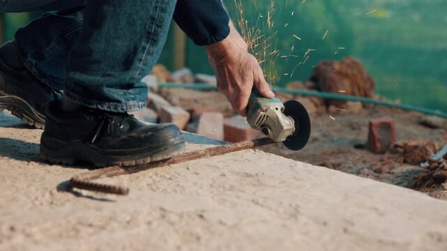 Hands, metal and grinder at construction site to cut material with power tools, sparks or contractor. Man, machine and industry for renovation, expansion or engineering for repair and maintenance