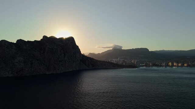 Sunrise behind Penon de Ifach cliffs with Calpe bay and skyline aerial view Spain