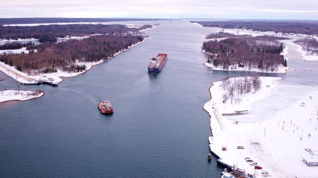 Cinematic drone shot of a large ship traveling toward the Soo Locks shipping canal