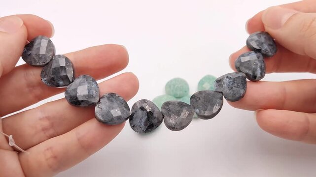 These grey labradorite heart beads feature a faceted finish and iridescent sheen on a strand, perfect for creating romantic jewelry pieces, necklaces, bracelets, and custom craft projects