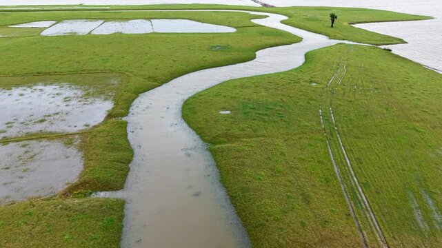 Aerial view of Tanguar Haor featuring a winding waterway through lush green wetlands and flooded fields in Sunamganj District, Sylhet Division, Bangladesh.