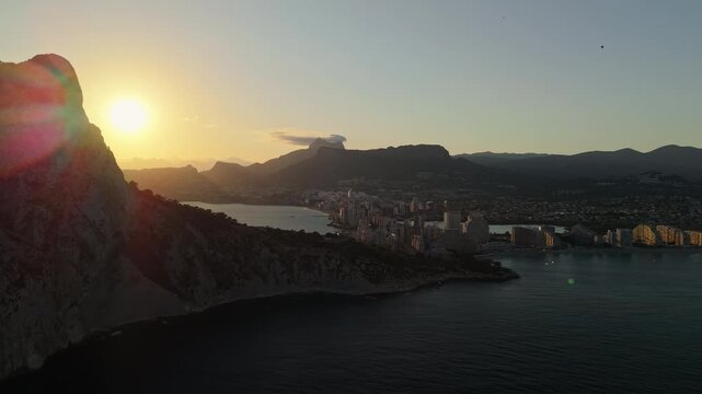 Sunrise beside Penon de Ifach cliffs with Calpe skyline and bay aerial view Spain