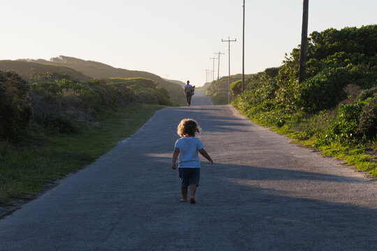 A child and mother walk down a road in a nature reserve at sunset