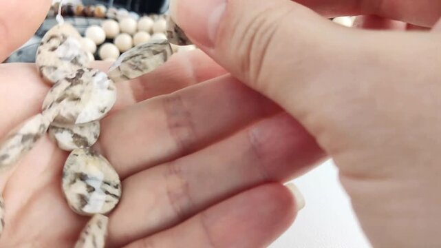 The elegant faceted teardrop stone beads feature intricate dark patterns on light cream backgrounds for unique and sophisticated jewelry crafting projects