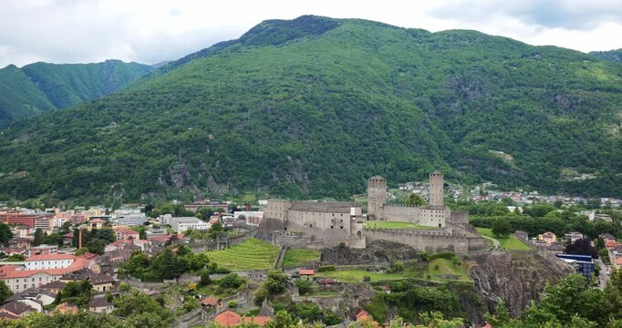 Bellinzona, Switzerland, May 18, 2026. High angle panning shot focusing on the historic medieval Castelgrande fortress complex, overlooking the Swiss town and lush green mountain slopes