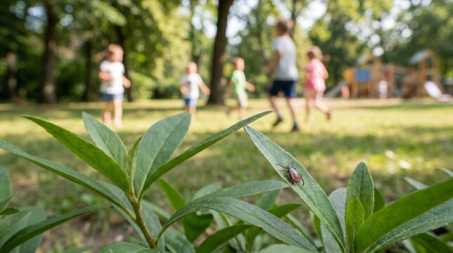 Tick crawling on green leaf in park near playing children. Parasite danger and risk of infection during summer activity. Warning about insect bite and health protection in nature.