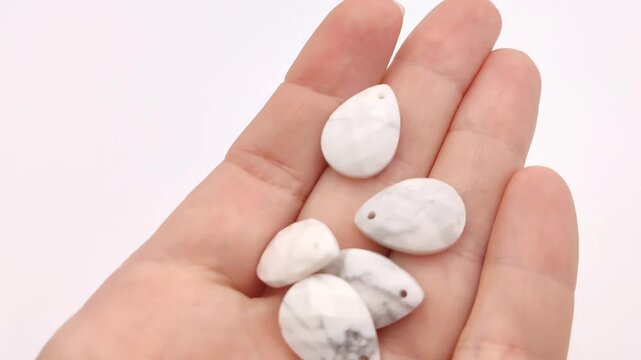 These white howlite teardrop pendants feature faceted surfaces and gray veining for elegant jewelry making projects that require a sophisticated and natural stone aesthetic for custom designs