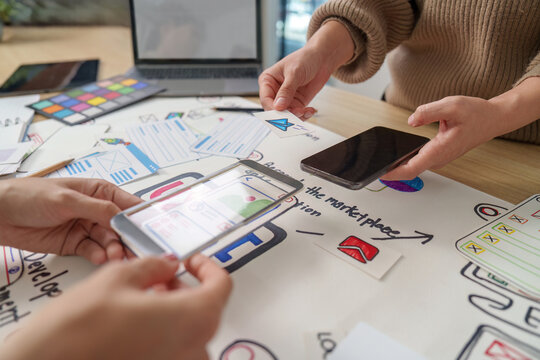 Women designers using transparent phone for AR mobile app UI UX prototyping