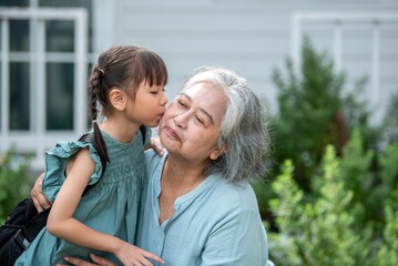 Obraz premium Grandmother encouraging granddaughter before going to school showing love and emotion support in family bonding. Portrait of senior woman and grandchild in uniform hugging with smile in garden.