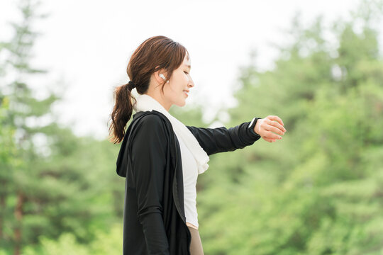 A woman using a smartwatch while exercising (healthcare, music, workout).