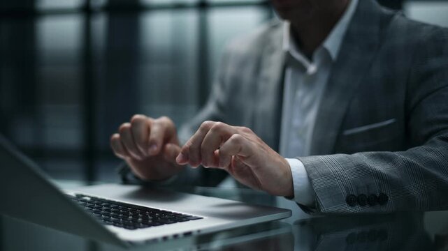 Man in business attire types on laptop