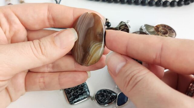 This smooth oval banded agate stone features intricate natural swirl patterns and earthy tones for high quality custom jewelry crafting and bespoke accessory creation