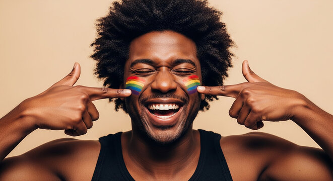 Man with rainbow face paint smiles with eyes closed, pointing to cheek, representing pride, diversity, and celebration, ideal for LGBTQ+ themes.