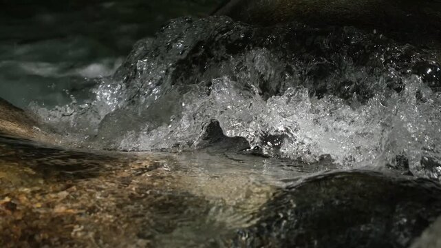 Silent clear mountain stream water splashing over rocks close up