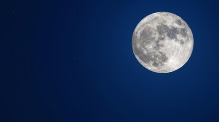 Fototapeta premium A bright, detailed full moon shines in the dark, clear night sky, showcasing its craters and surface.