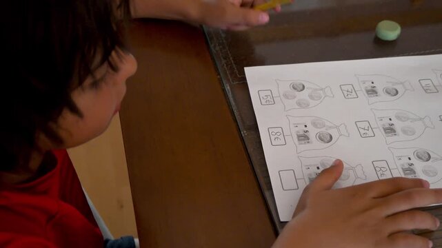 Young child practicing mathematics homework with pencil