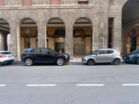 Black Range Rover Sport and silver Suzuki Ignis parked on city street