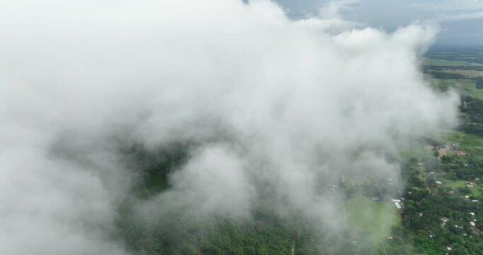 Aerial view of Tanguar Haor partially obscured by thick white clouds over lush green vegetation and rural settlements in Sunamganj District, Sylhet Division, Bangladesh.