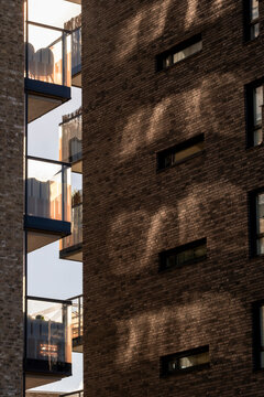 Brick shadows cross an Oslo apartment building in Norway, where modern residential architecture holds balcony edges against warm facade texture