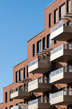 Clear blue sky beside a brick apartment building in Oslo, Norway, where modern residential architecture steps upward through white balcony blocks