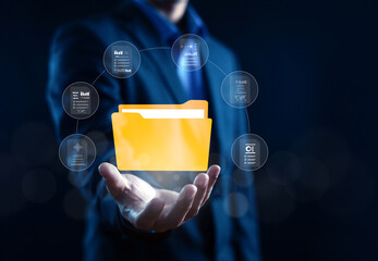 Businessman holding digital folder icon with floating document interface. Concept for cloud storage, data management, information security, digital transformation, and business workflow organization. © wasan